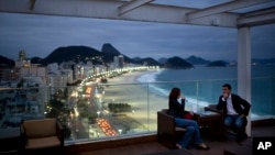 FILE - Tourists sit in a bar at a hotel overlooking Copacabana beach, in Rio de Janeiro, Brazil, Aug. 16, 2013.