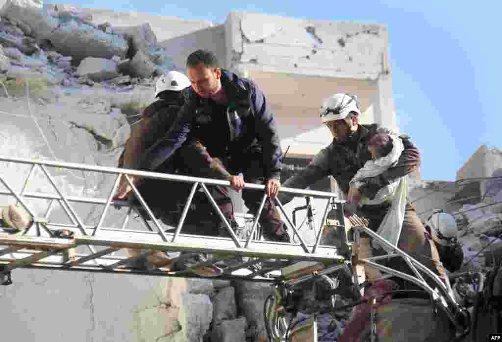 Syrian Civil Defense members evacuate a toddler from the rubble of buildings destroyed following Russian air strikes in the northwestern city of Idlib, on May 30, 2016.