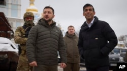 FILE - In this photo provided by the Ukrainian Presidential Press Office, Ukrainian President Volodymyr Zelenskyy, left, and British Prime Minister Rishi Sunak look at destroyed Russian military vehicles in downtown Kyiv, Ukraine, Nov. 19, 2022. 