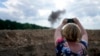 FILE - A journalist takes a picture of smoke rising from a landmine exploded by a Ukrainian specialized team working on a field to clean the area on the outskirts of Kyiv, Ukraine, June 9, 2022. 