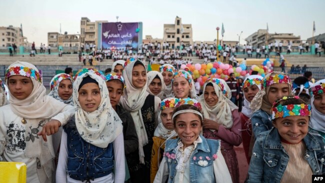 فتيات يقفن على أرض الملعب خلال حفل افتتاح "كأس العالم للمخيمات" في ملعب إدلب البلدي الذي أعيد افتتاحه حديثًا في المدينة الواقعة شمال غرب سوريا التي يسيطر عليها المتمردون في 19 تشرين الثاني / نوفمبر 2022.