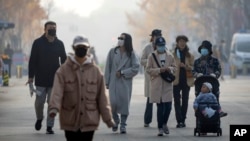 People wearing face masks walk along a pedestrian shopping street at the Wangfujing shopping district in Beijing, Nov. 19, 2022. 