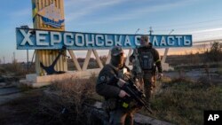 Two members of the Ukrainian defense forces stand next to a sign reading 'Kherson region' on the outskirts of Kherson, southern Ukraine, Nov. 14, 2022.