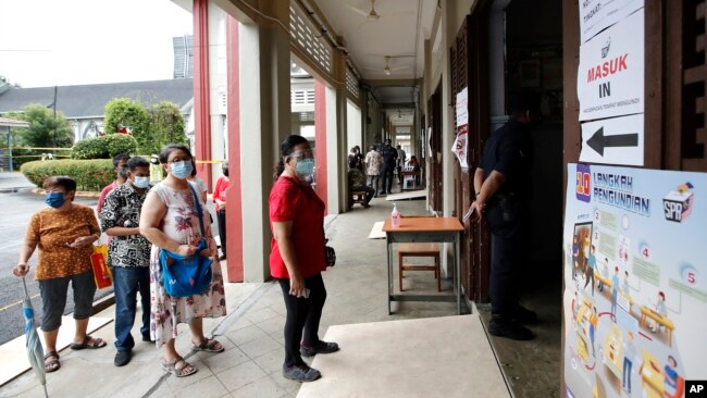 Voters wait in a line to cast their ballots for general election at a polling station in Kuala Lumpur, Malaysia, Nov. 19, 2022.