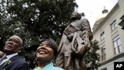 The Rev. Bernice King, right, daughter of the Rev. Martin Luther King Jr., stands under a statue paying tribute to her father, after it's unveiled on the state Capitol grounds in Atlanta, Monday, Aug. 28, 2017. 