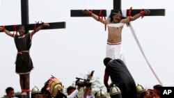 Dua pria digantung di kayu salib saat memperagakan kembali penderitaan Yesus Kristus sebagai bagian dari perayaan Jumat Agung di San Pedro Cutud, Provinsi Pampanga, Filipina utara, 30 Maret 2018. (Foto: AP)