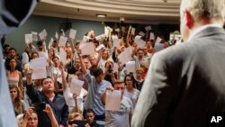 Theater staff show their resignation letters to Yuri Bondar, Belarusian Minister of Culture, in the Janka Kupala National Theater in Minsk, Belarus, Tuesday, Aug. 18, 2020. They handed in their notice after the theater's director, Pavel Latushko, was fired. (AP Photo)