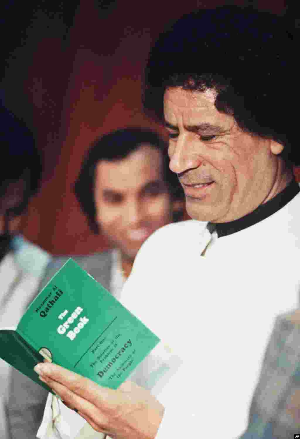 资料照片: 利比亚领导人卡扎菲在利比亚看他自己写的绿皮书。1984年1月5日。(法新社)