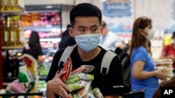 A man wearing a protective mask looks for the start of the queue at a grocery store in Taguig, metropolitan Manila, Philippines, March 13, 2020.