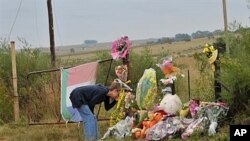 A supporter of African far-right leader Euguene Terre'Blanche looks at flowers and pays tribute in front of the entrance of the farm in Ventersdorp, 05 Apr 2010