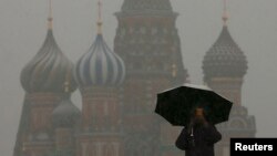 FILE - A man walks under an umbrella during a snowfall in Red Square in central Moscow March 31, 2014.