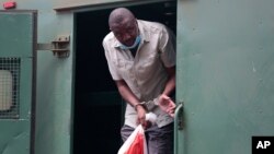 Zimbabwe's investigative journalist Hopewell Chin’ono gets out of a prison van at the magistrates courts in Harare, Nov. 6, 2020.