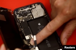 An employee checks an Apple iPhone 12 in a mobile phone store in Nantes, France on September 13, 2023. (REUTERS/Stephane Mahe)