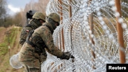 Солдаты строят забор из колючей проволоки на границе Польши с российским Калининградом близ города Больце, Польша, 3 ноября 2022 года
