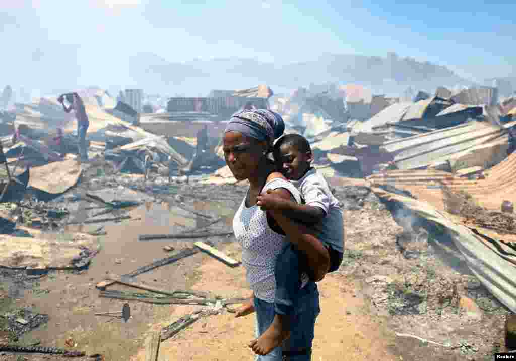 A woman and a child look at the destruction as a blaze destroyed many shacks in Masiphumelele township in Cape Town, South Africa. REUTERS/Esa Alexander