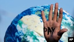 A hand of a protester reads "pay" amid calls for reparations for loss and damage at the COP27 U.N. Climate Summit, in Sharm el-Sheikh, Egypt, Nov. 18, 2022.