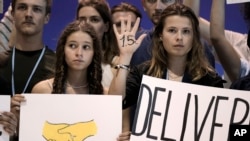 Samira Ghandour, left, and Luisa Neubauer, both of Germany, hold signs encouraging world leaders to maintain policies limiting warming to 1.5 degrees Celsius and provide reparations for loss and damage at the COP27 U.N. Climate Summit, Nov. 19, 2022, in Sharm el-Sheikh, Egypt.