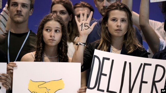 Samira Ghandour, left, and Luisa Neubauer, both of Germany, hold signs encouraging world leaders to maintain policies limiting warming to 1.5 degrees Celsius and provide reparations for loss and damage at the COP27 U.N. Climate Summit, Nov. 19, 2022, in Sharm el-Sheikh, Egypt.
