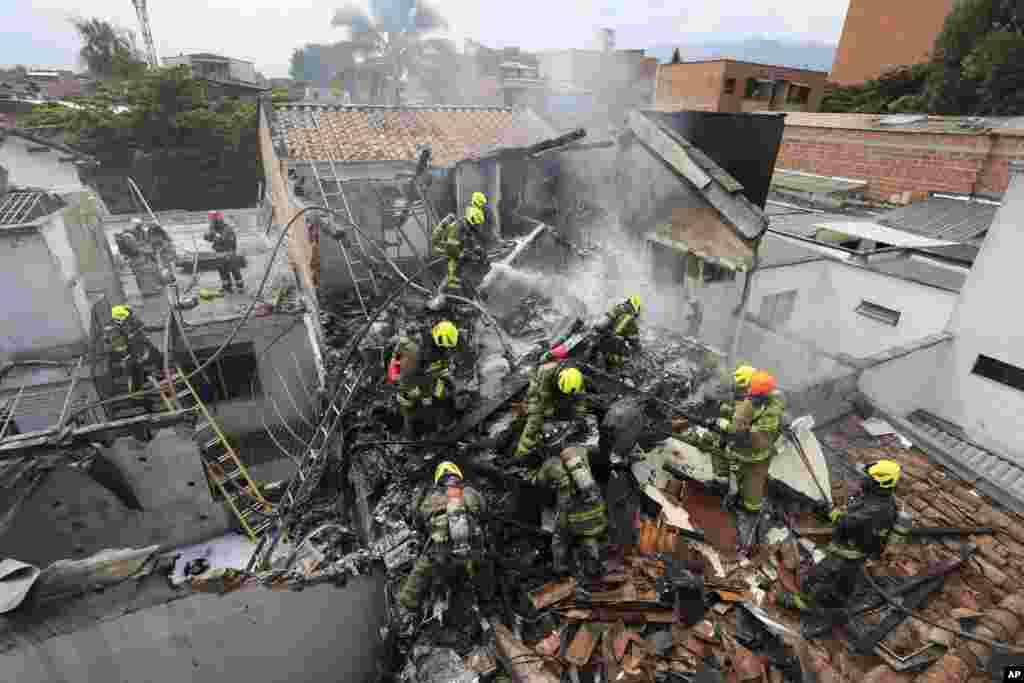 Firefighters work at the crash site of a small plane that fell on top of homes in a residential area of Medellin, Colombia.&nbsp;The plane crashed shortly after taking off from Medellin&#39;s Olaya Herrera airport, killing at least eight people including two members of the crew and his six passengers, according to city Mayor Medellin Daniel Quintero. (AP Photo/Jaime Saldarriaga)