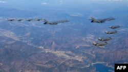 Dua jet pembom AU AS (atas C), jet tempur AU Korsel (kanan) terbang di atas Semenanjung Korea Selatan selama latihan udara bersama. Kedua negara terlibat dalam pembicaraan yang dapat memberi Seoul peran lebih besar dalam pengoperasian kekuatan nuklir AS, (Foto: AFP)