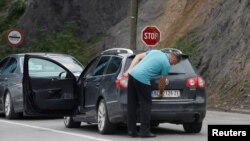 FILE - A driver removes a sticker covering the national markings on his car plates at the Jarinje border crossing, Kosovo, Sept. 1, 2022. 