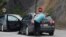 FILE - A driver removes a sticker covering the national markings on his car plates at the Jarinje border crossing, Kosovo, Sept. 1, 2022. 