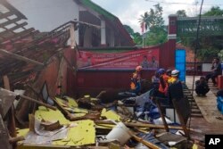 In photo released by Indonesian National Search and Rescue Agency (BASARNAS), rescuers inspect a school damaged by earthquake in Cianjur, West Java, Indonesia, Monday, Nov. 21, 2022. (BASARNAS via AP)