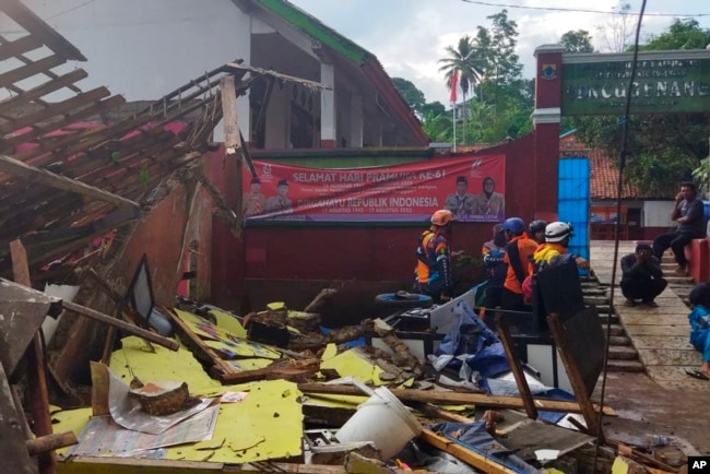 In photo released by Indonesian National Search and Rescue Agency (BASARNAS), rescuers inspect a school damaged by earthquake in Cianjur, West Java, Indonesia, Monday, Nov. 21, 2022. (BASARNAS via AP)