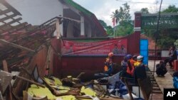 In photo released by Indonesian National Search and Rescue Agency (BASARNAS), rescuers inspect a school damaged by earthquake in Cianjur, West Java, Indonesia, Monday, Nov. 21, 2022. (BASARNAS via AP)
