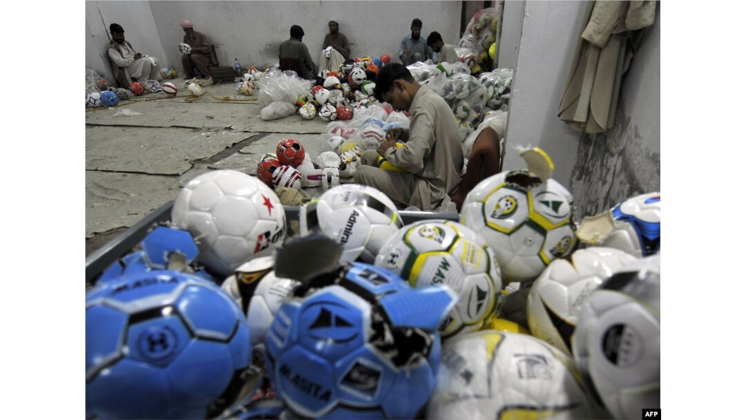 FILE - In this picture taken on Feb. 23, 2010, Pakistani workers stitch footballs at a factory in Sialkot.