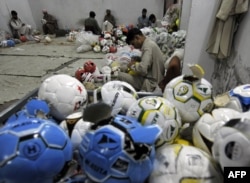 FILE - In this picture taken on Feb. 23, 2010, Pakistani workers stitch footballs at a factory in Sialkot.