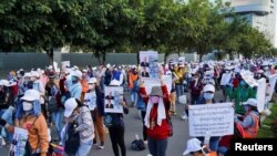 NagaWorld casino workers hold up placards during a protest outside the National Assembly building after several union members were arrested in Phnom Penh on January 5, 2022. (Cindy Liu/Reuters)