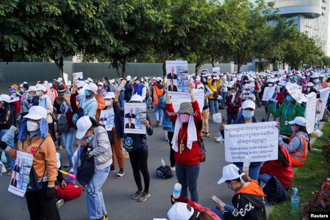 FILE - NagaWorld casino workers hold up placards during a protest outside the National Assembly building after several union members were arrested, in Phnom Penh, Cambodia, Jan. 5, 2022.