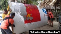 资料照：菲律宾海岸警卫队发布的照片显示，菲律宾海岸警卫队队员在曼布劳海岸外捞起的一块有着中国长征-5B号标识的残片。（2022年8月）