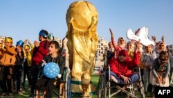 Children pose by a mock FIFA World Cup trophy during the opening ceremony of the "Camps World Cup" at Idlib Municipal Stadium in Syria on Nov. 19, 2022. More than 300 children in rebel-held northwest Syria participated in their own football World Cup that day.