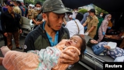 A man carries an injured child to receive treatment at a hospital, after an earthquake hit in Cianjur, West Java province, Indonesia, November 21, 2022, in this photo taken by Antara Foto. (Antara Foto/Yulius Satria Wijaya via REUTERS)