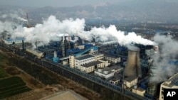 FILE - Smoke and steam rise from a coal processing plant in Hejin in central China's Shanxi Province, Nov. 28, 2019.