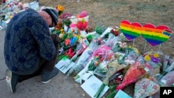 A man prays at a makeshift tribute with a display of bouquets of flowers on Nov. 21, 2022, a day after a shooting at the LGBT nightclub Club Q in Colorado Springs, Colo. 