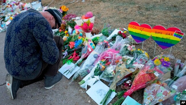 A man prays at a makeshift tribute with a display of bouquets of flowers on Nov. 21, 2022, a day after a shooting at the LGBT nightclub Club Q in Colorado Springs, Colo.