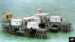 A Chinese flag and a satellite dish are prominently displayed in a structure built by China in one of the islands in the Spratly Islands.