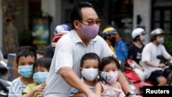 A man and his children, all wearing protective masks, ride a bicycle on a street during the coronavirus disease (COVID-19) outbreak, in Hanoi, Vietnam, July 27, 2020. 