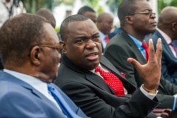 Former Major General Sibusiso Moyo, center, who was appointed Foreign Affairs and International Relations Minister speaks with a fellow minister, before taking the oath of office, Dec. 4, 2017, in Harare.