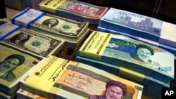 FILE - Iranian and U.S. banknotes are on display at a currency exchange shop in Tehran, April 4, 2015.