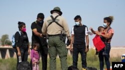 Migrantes de Guatemala esperan ser procesados después de entregarse a las autoridades en la frontera entre Estados Unidos y México el 12 de mayo de 2021 en Yuma, Arizona.
