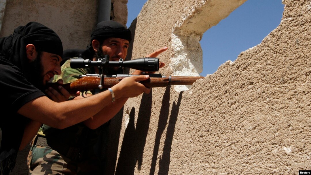 A member of the Free Syrian Army points as his fellow fighter aims his weapon, near the air force intelligence headquarters in Aleppo, Aug. 1, 2013.