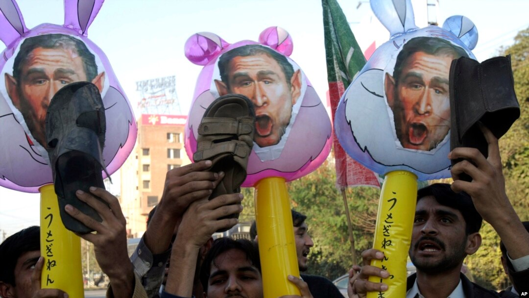 FILE - Pakistani protesters hold up shoes and caracatures of U.S. President George W. Bush during a demonstration in support of Iraqi journalist Muntadhar al-Zeidi in Lahore, Pakistan, Dec. 21, 2008. 