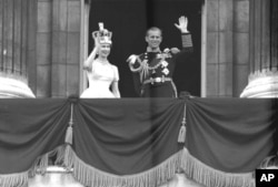 Ratu Inggris Elizabeth II dan Pangeran Philip, Duke of Edinburgh, melambaikan tangan mereka kepada para pendukungnya dari balkon di Istana Buckingham, setelah penobatannya di Westminster Abbey. London, Juni. 2, 1953. (AP Photo/Imam)