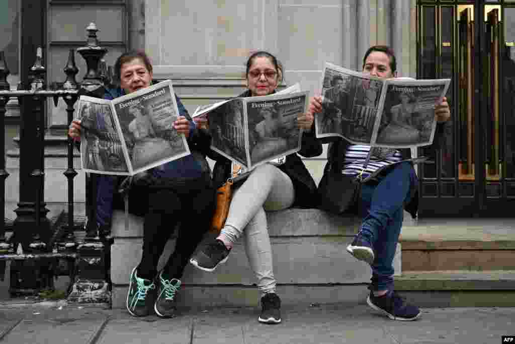 Three Guatemalan tourists read London's main free newspaper The Evening Standard in central London, a day after Queen Elizabeth II died at the age of 96.