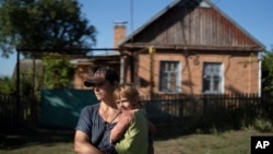 Natalia Stokoz holds her daughter Veronika, 3, as they stand near their house in the village of Zorya, about 20 kilometers from the Zaporizhzhia nuclear power plant, Sept. 2, 2022. Stokoz says that it's not the shelling that scares her most but the risk of a radiation leak.