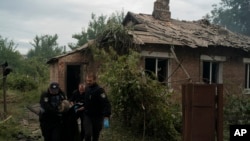 Police officers carry a bag containing the body of a person killed in his house after a Russian attack in Pokrovsk region, Ukraine, Sept. 11, 2022. 